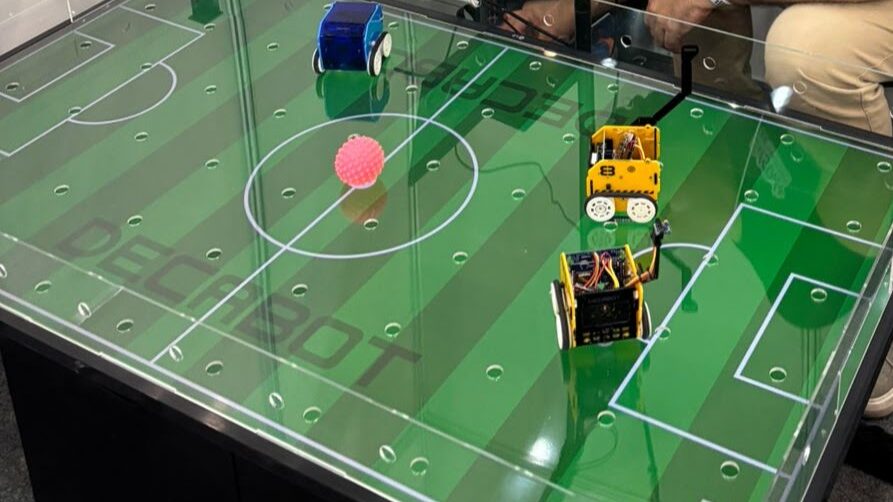 Arena Decabot na forma de um campo de futebol com 3 robôs Decabot em cima.